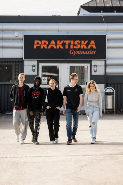 Fem elever går mot kameran utanför skolan