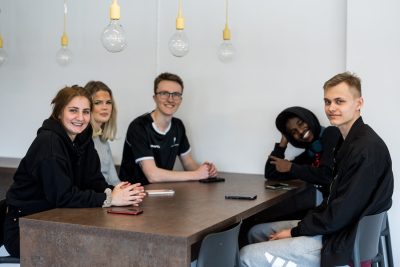 Fem elever sitter vid ett bord i skolans gemensamma lokaler