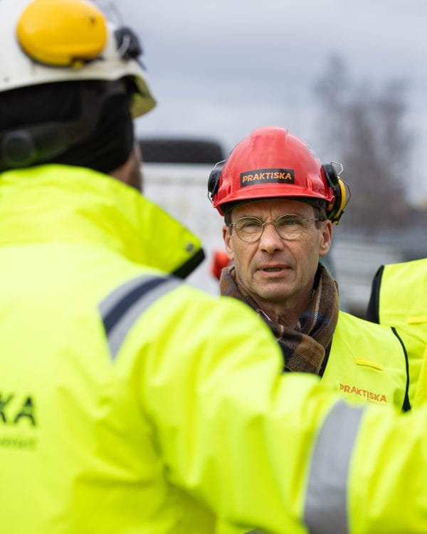 Statsministern i en bygghjälm som det står Praktiska på