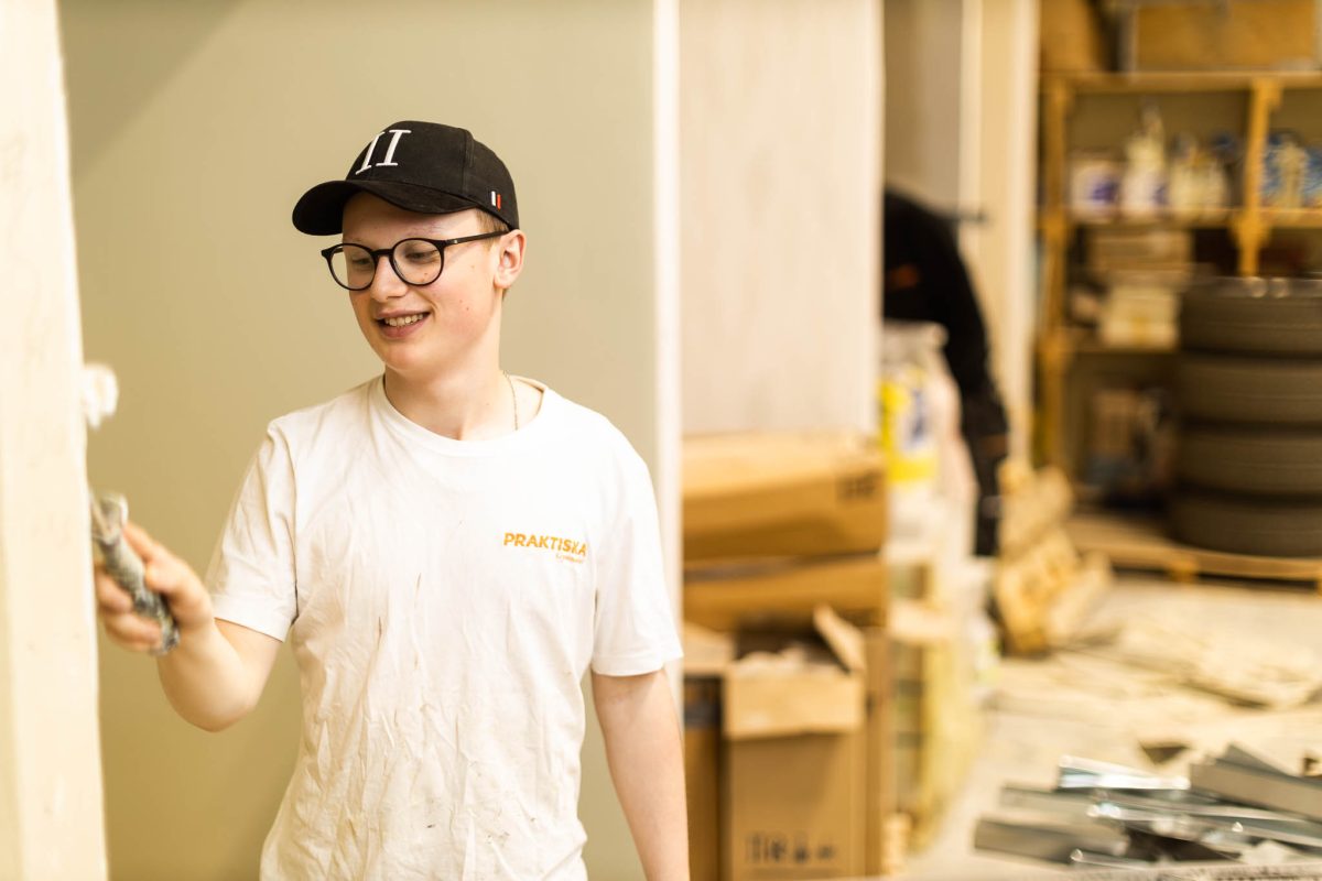 Elev målar en vägg med roller