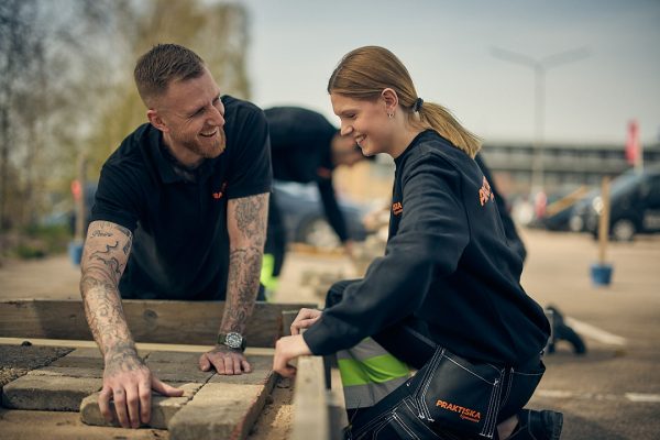 En lärare som visar en elv hur man lägger marksten