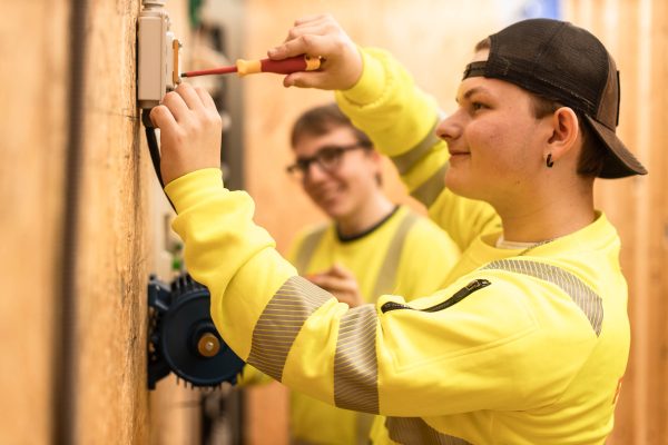 Två elever på Automation installerar ett system på en vägg.
