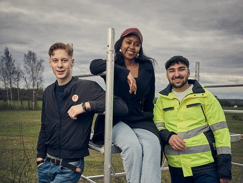 Tre elever på Praktiska som sitter på och hänger vid en byggställning.