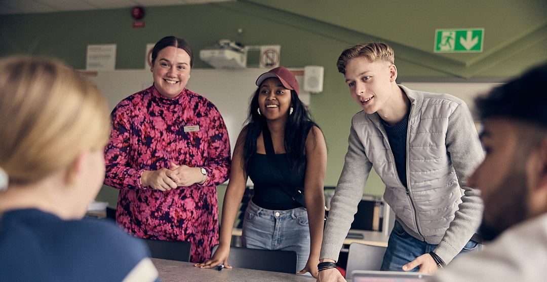 Två elever och en lärare som lyssnar på en elev som pratar på Praktiska Gymnasiet