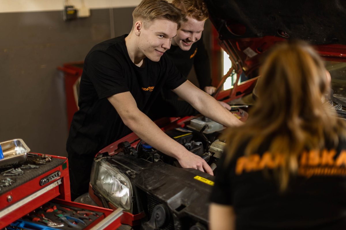 Tre elever mekar med en personbil i ett garage