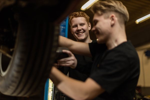 Två elever på personbil byter däck på en bil.