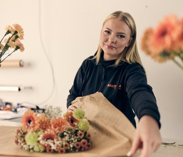 En floristelev som slår in en bukett blommor.