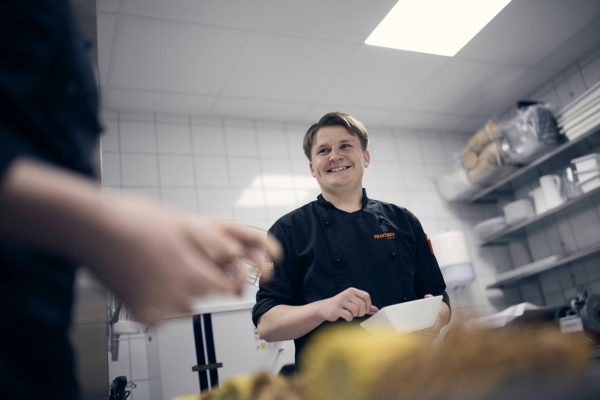 Elev som rör om i en sås i restaurangköket på skolan.
