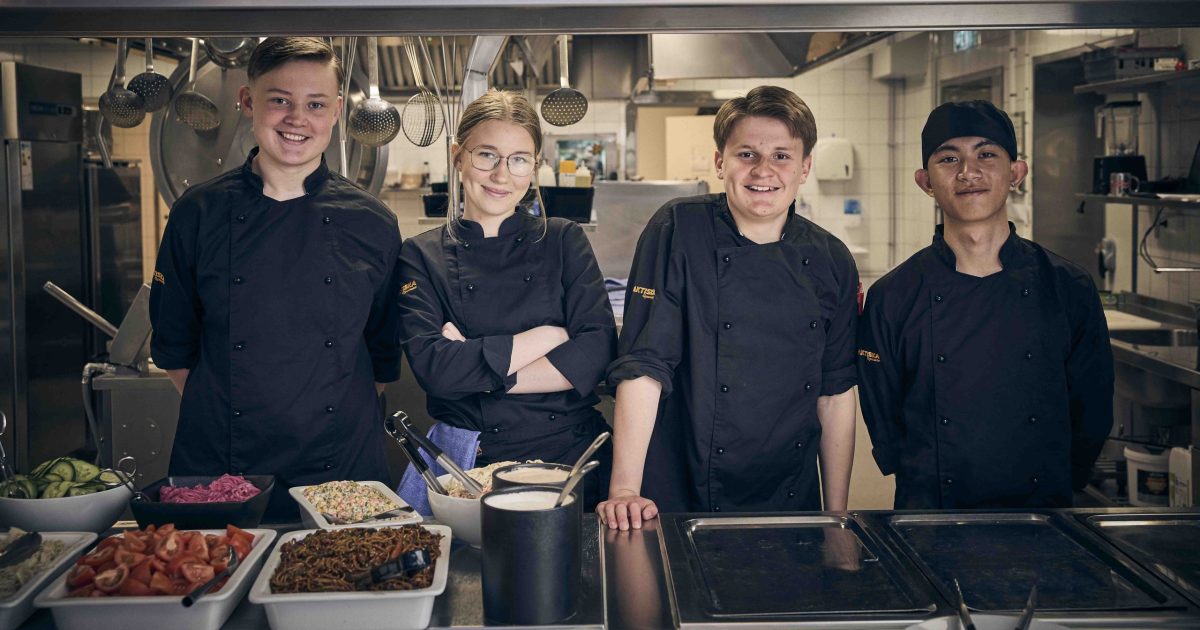 Fyra elever som står i ett restaurangkök.