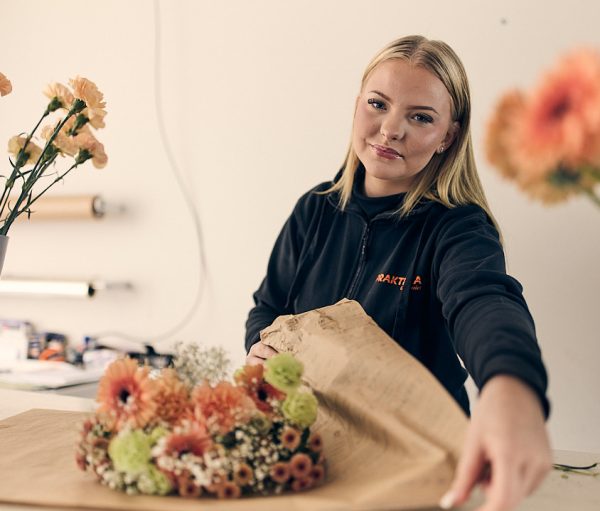 En floristelev som slår in en blombukett.