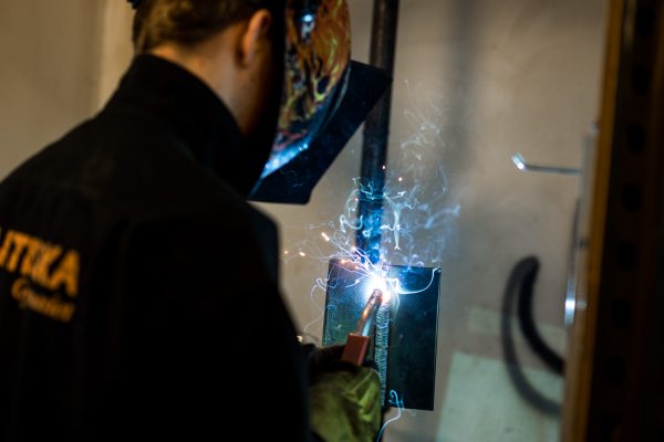Elev på svetsteknik svetsar på en metallplatta.