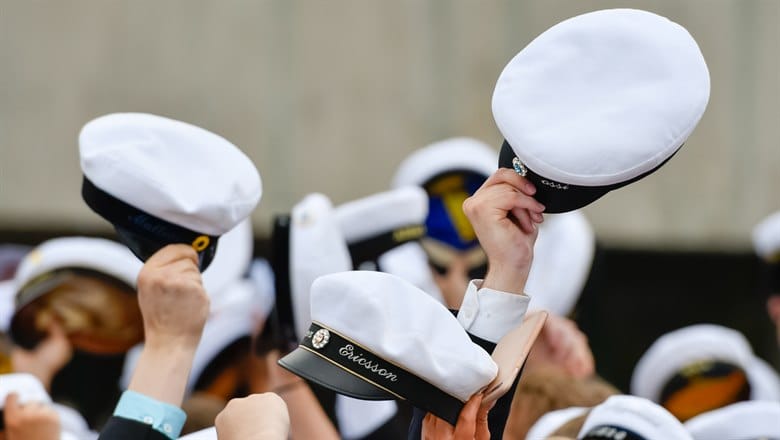 Händer som håller upp studentmössor i luften.