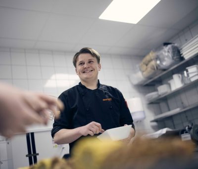 Elev som rör en sås i skolans restaurangkök.