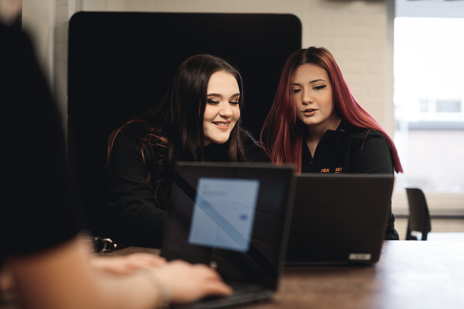 Två elever sitter i skolans lokaler med en laptop
