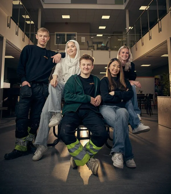 Fem elever på Praktiska som sitter vid ett bord och tittar in i kameran.