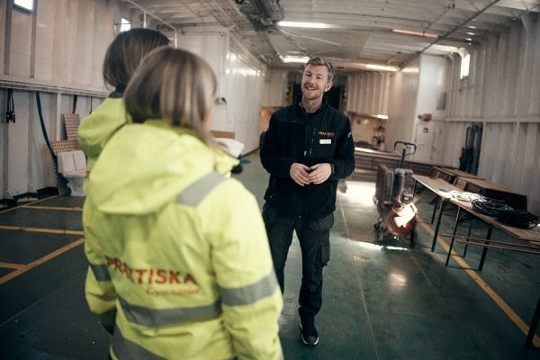 En man som står och pratar inför två elever på ett fartyg