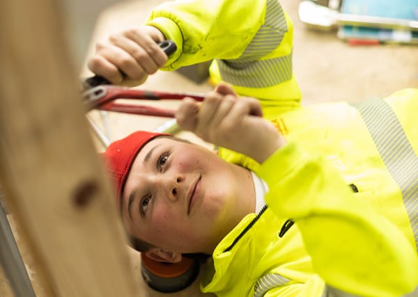 En elev ligger på golvet och arbetar med ett verktyg