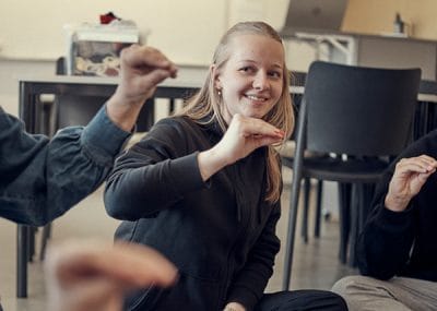 En elev som ler och gör teckenspråk