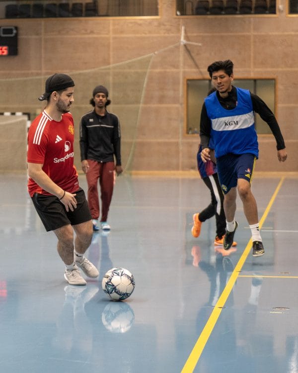 Fyra killar som spelar fotboll i en idrottssal.