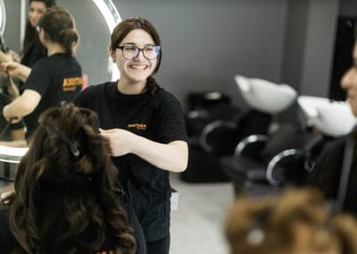 En elev ser glad ut och stylar en persons hår