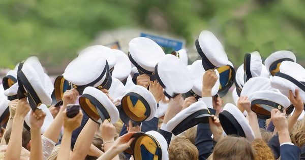 Massvis med studentmössor som blir viftade i luften.