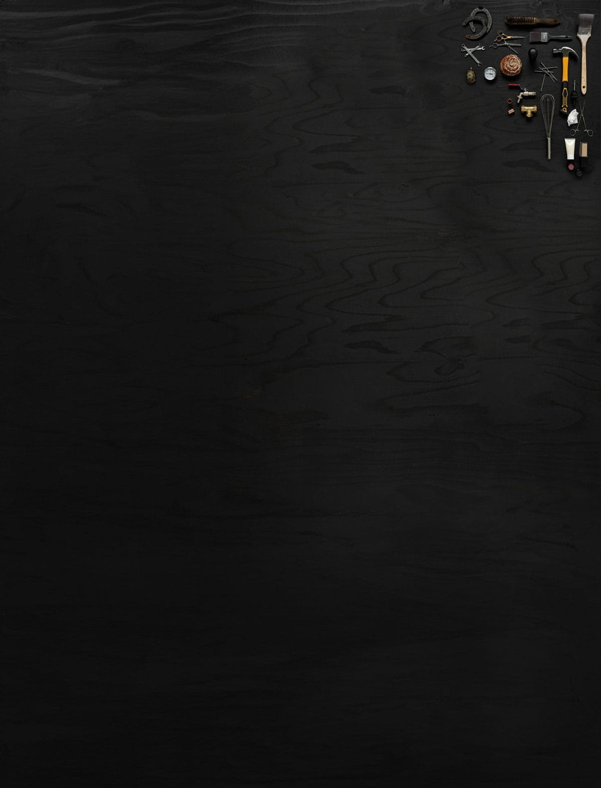 Föremål som representerar Praktiska Gymnasiets yrkesprogram ligger utlagda på mörkt trä.