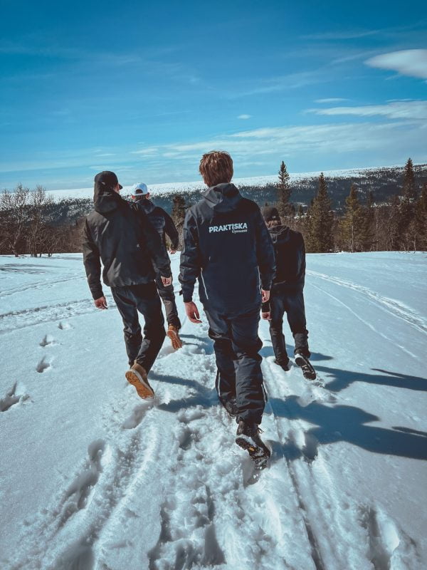 4 elever som läger naturturism är ute och går i snö en solig dag.