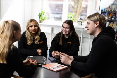Fyra elever sitter runt ett bord i skolan och pratar