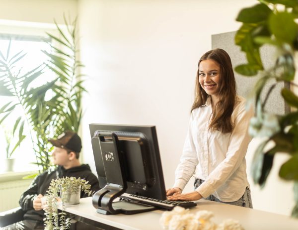 Elev som står vid en reception och tittar in i kameran