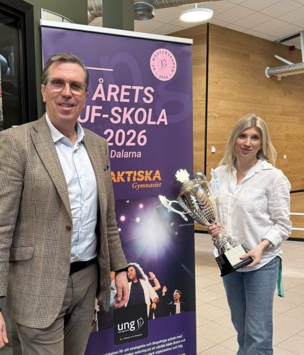 Två personer står stolt och håller vinstpokalen i handen.